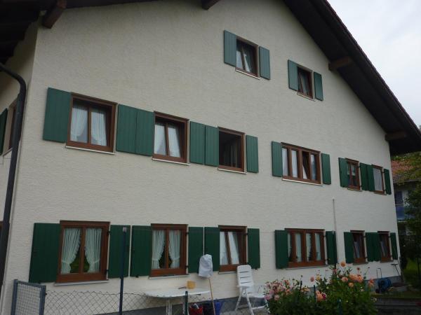 Hausfassade mit Holzfenstern und grünen Klappläden renoviert